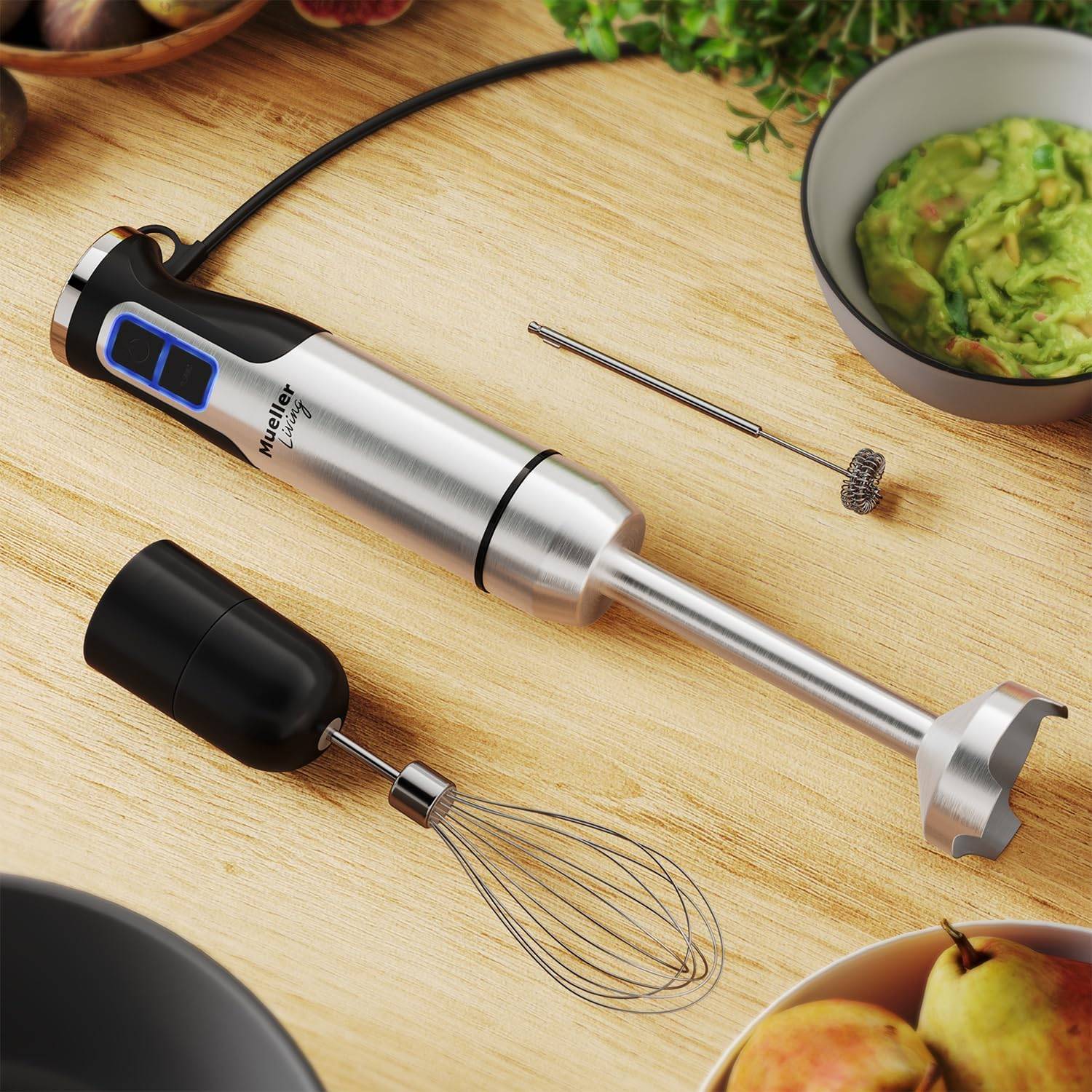 An immersion blender laying on a counter next to some attachments.