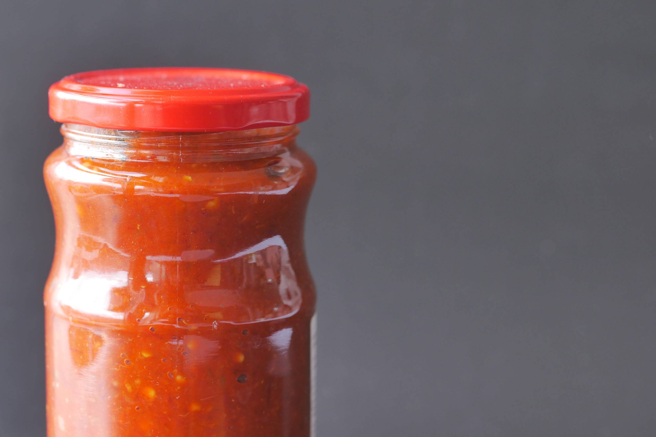 Tomato sauce in a small jar with a red lid.  