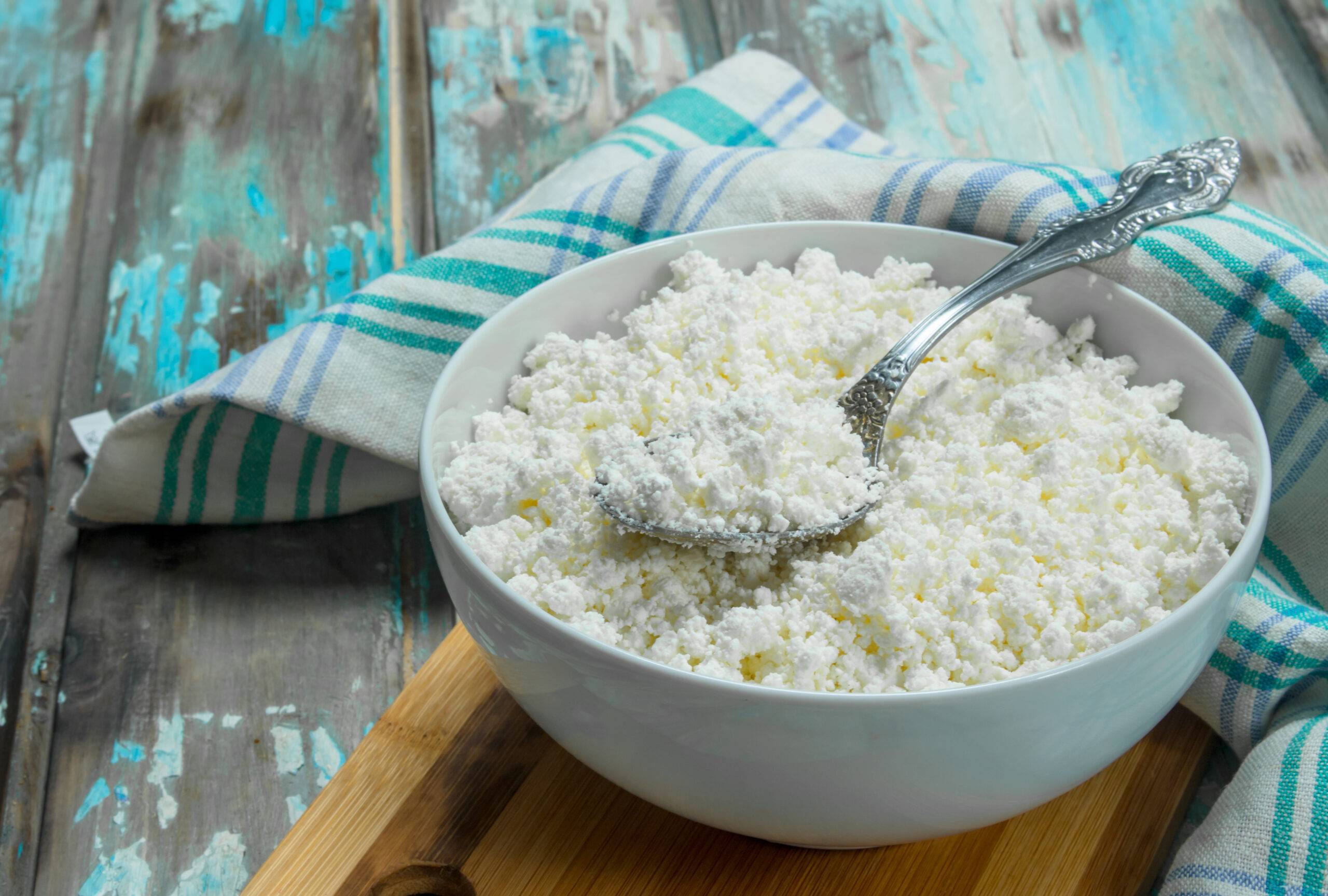 Cottage cheese in bowl on napkin. On a rustic background.