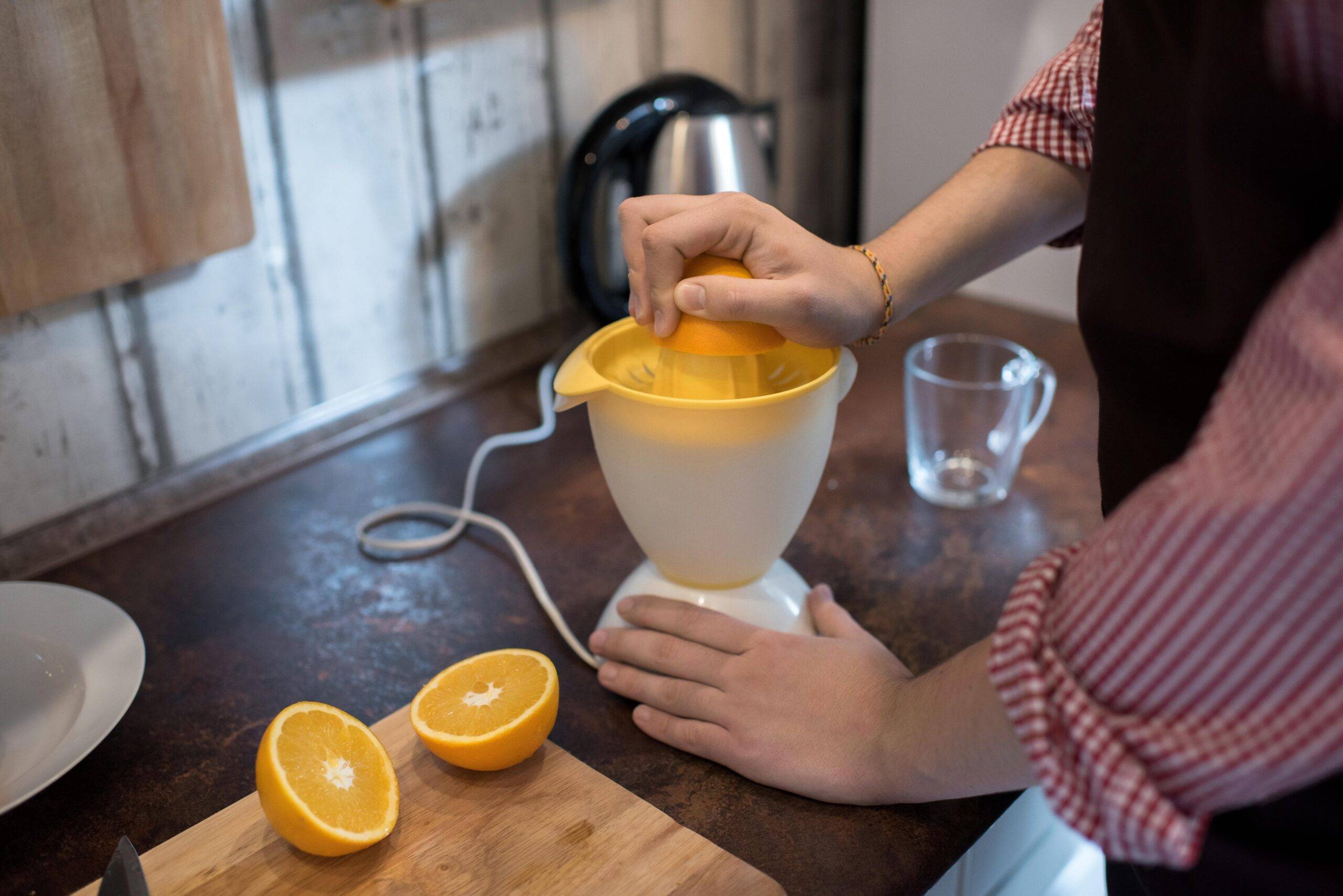 A person pressing an orange half into a juicer.