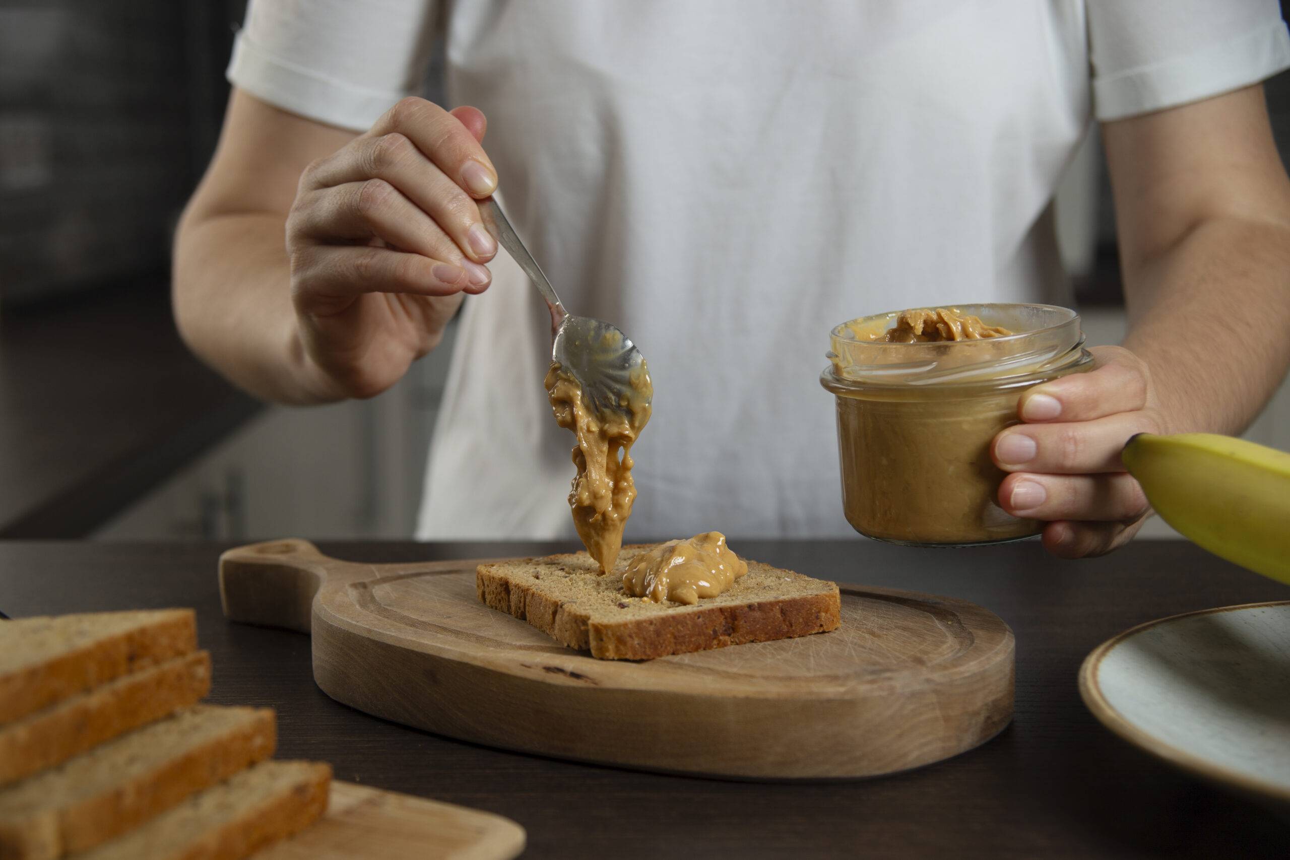 Women spreading a spoonful of peanut butter on a piece of bread.
