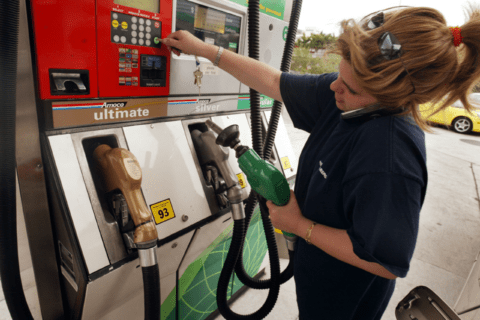 Woman on cellphone while using a gas pump.
