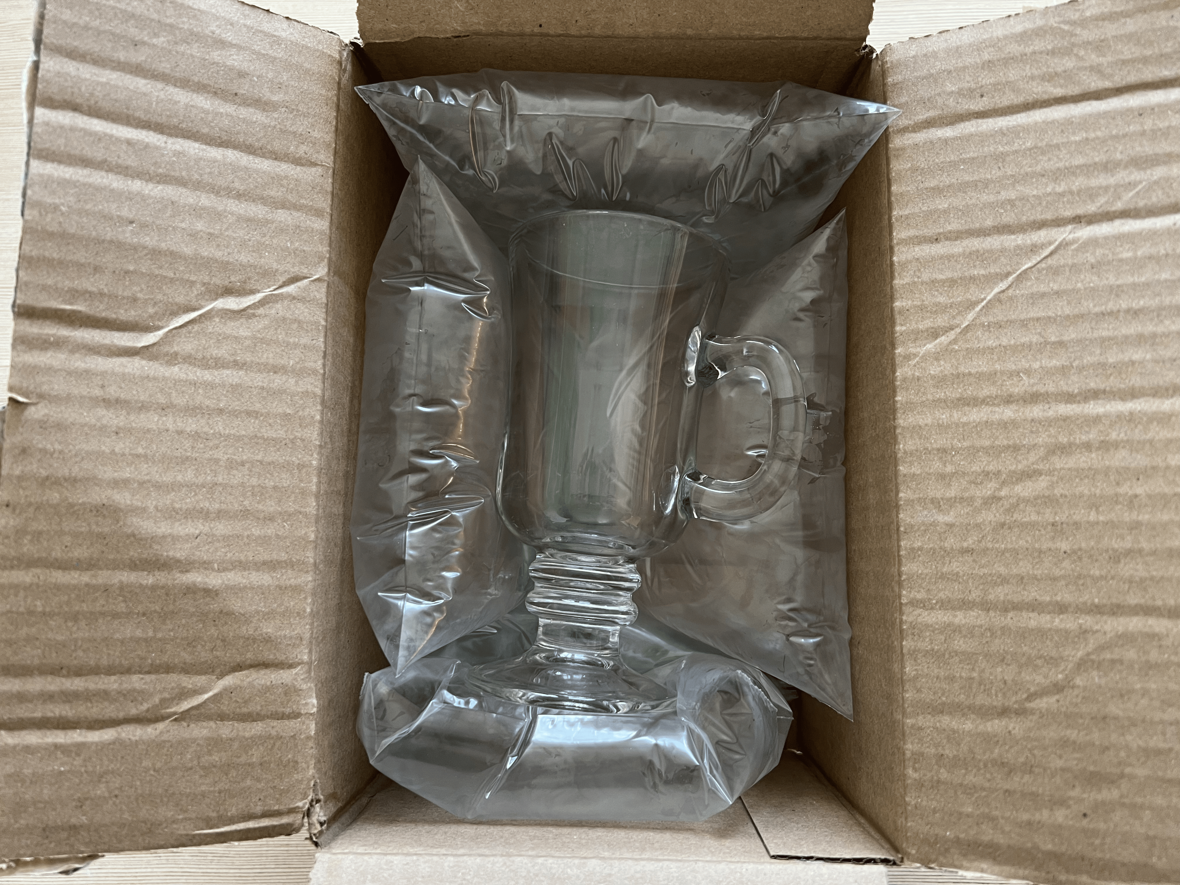 A glass in a small shipping box with inflated Ziploc bags serving as bubble wrap.