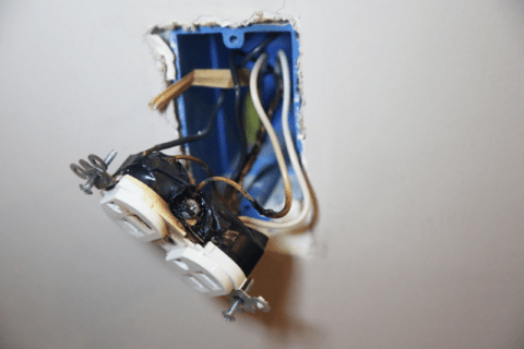 Exposed outlet wiring with burn marks.